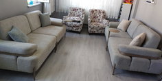Açık gri/bej modern kanepeler ve çiçek desenli berjerlerden oluşan salon takımı, metal ayaklar ve ahşap detaylarla tamamlandı. İnegöl mobilya Fiyatları kalitesiyle.