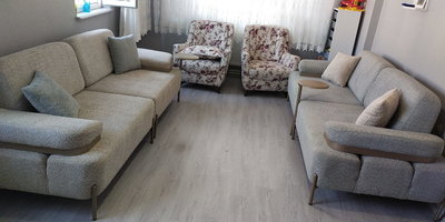 Açık gri/bej modern kanepeler ve çiçek desenli berjerlerden oluşan salon takımı, metal ayaklar ve ahşap detaylarla tamamlandı. İnegöl mobilya Fiyatları kalitesiyle.