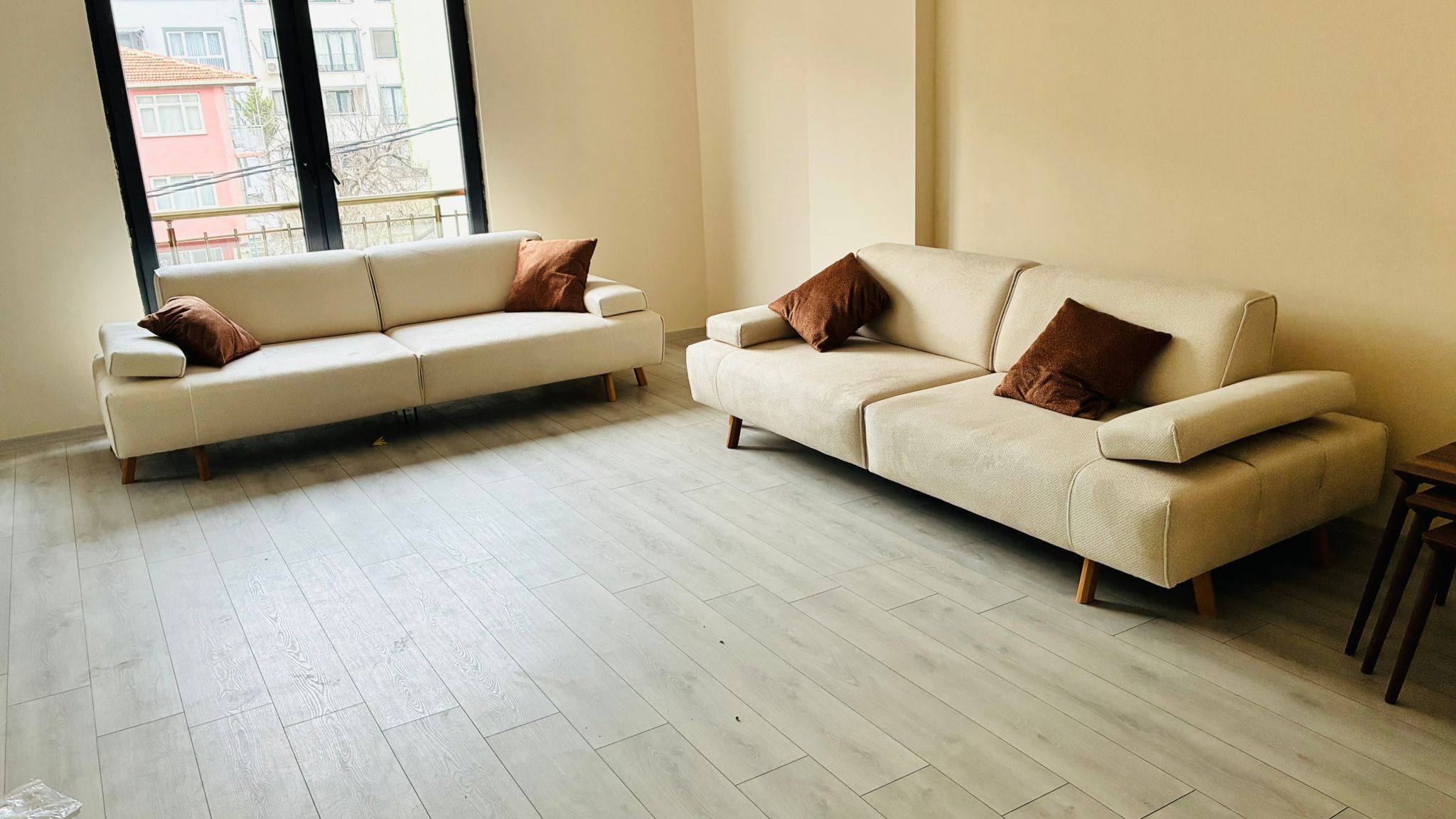 Ahmet Uğur B. 2026 modern beige sofa set featuring clean lines, wooden legs, and comfy brown throw pillows. Quality Inegol furniture for stylish homes.
