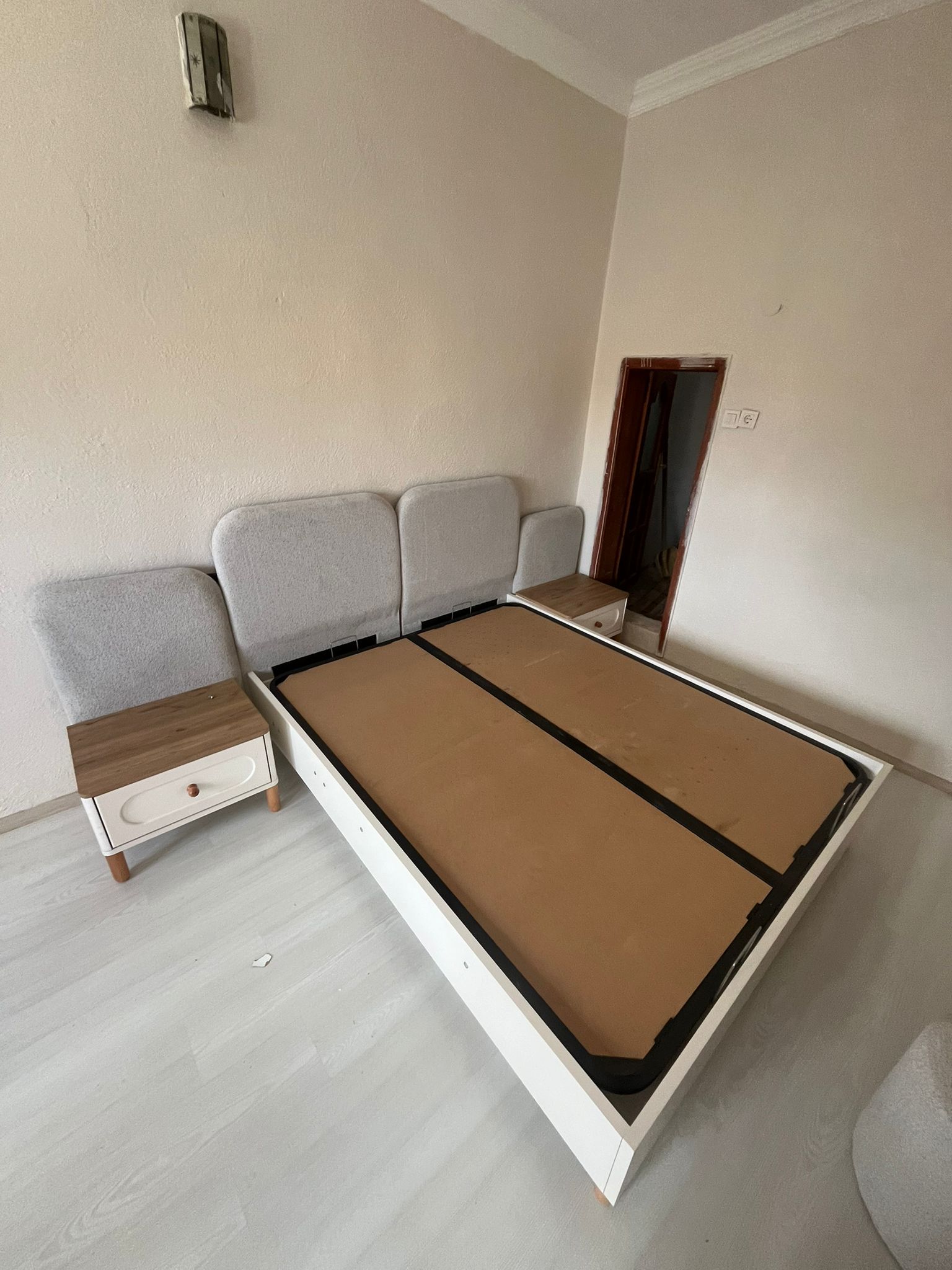 Modern designed white bed frame with a gray upholstered headboard and two matching nightstands with wood details. Quality İnegöl furniture brings style to your bedroom.