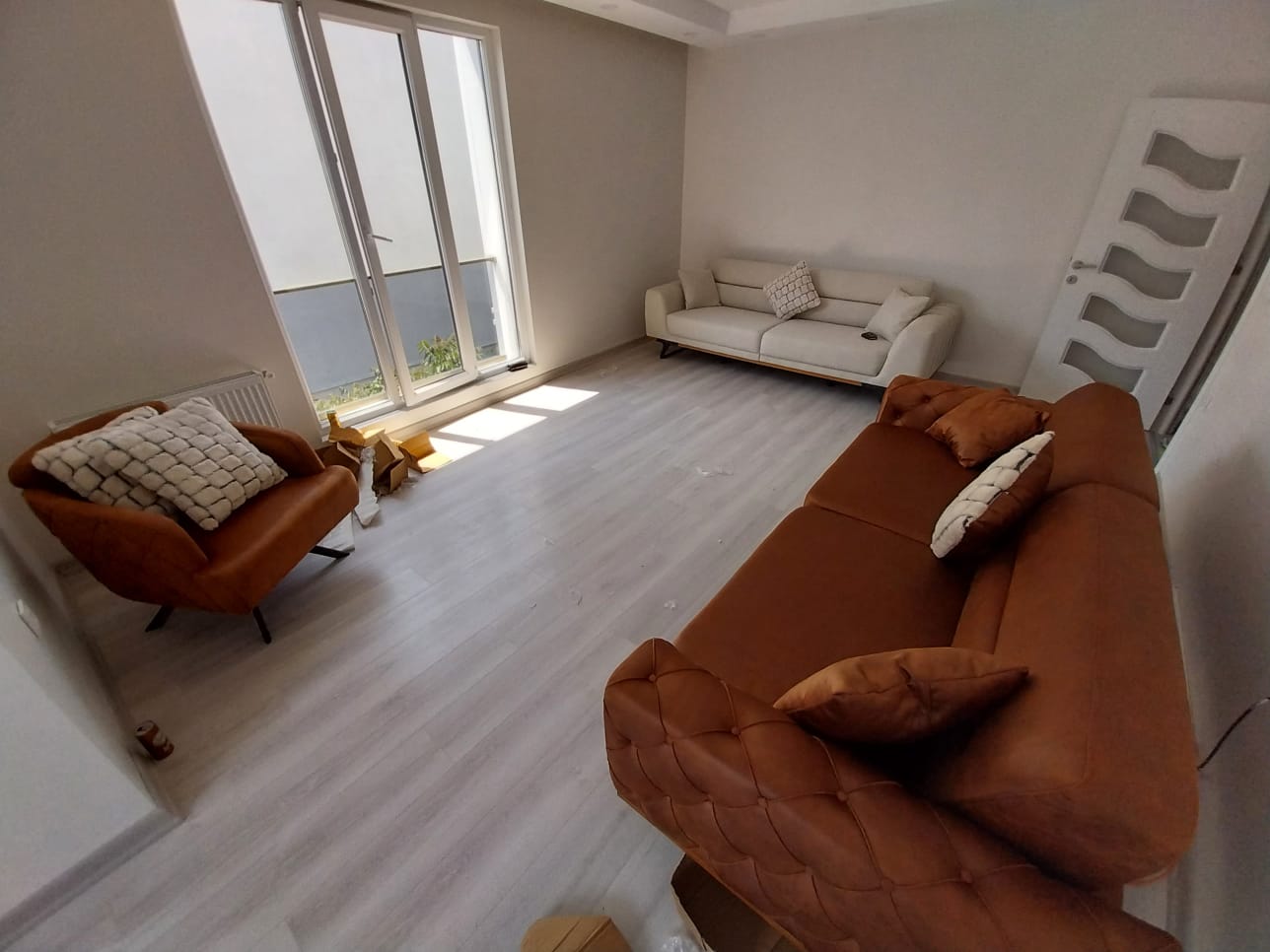 Bright living room with modern brown chesterfield sofa, cream sofas, and an armchair. Inegol furniture campaigns.