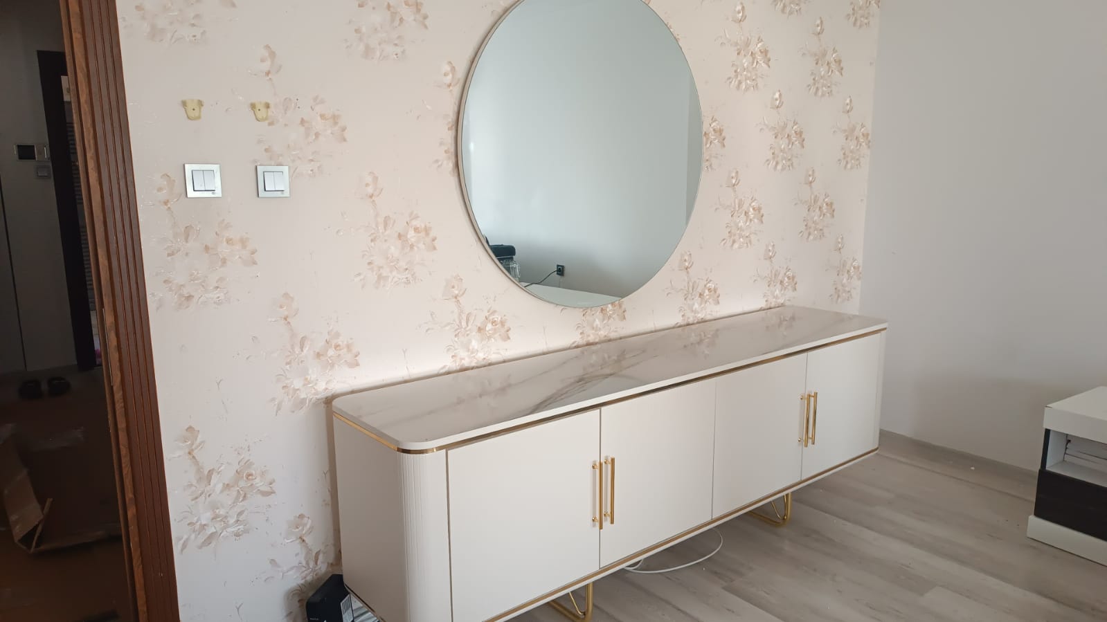 Aysegul Pala - Adana Inegol furniture console with marble-patterned white top. Modern interior with round mirror and gold accents.