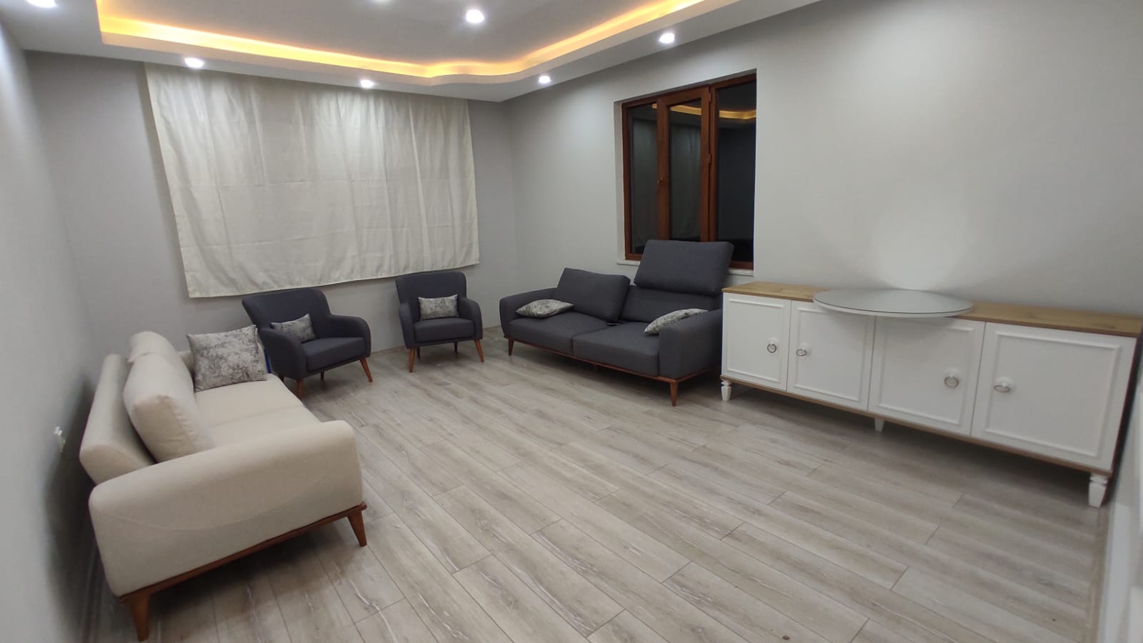 Modern living room set with grey and cream sofas, stylish sideboard, and armchairs. Showcasing the elegance of Modern inegol furniture.