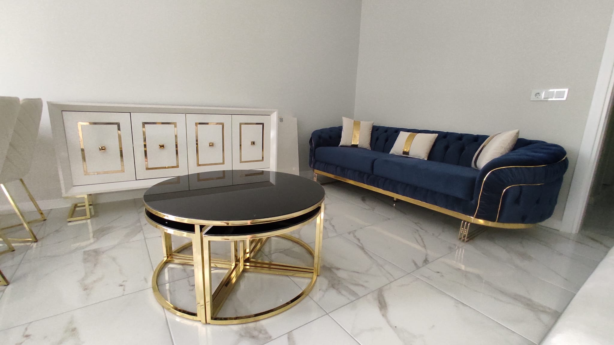 Modern luxury living room decor: Blue velvet sofa, black glass gold metal coffee table, white gold sideboard. Ideal for Inegol furniture prices.