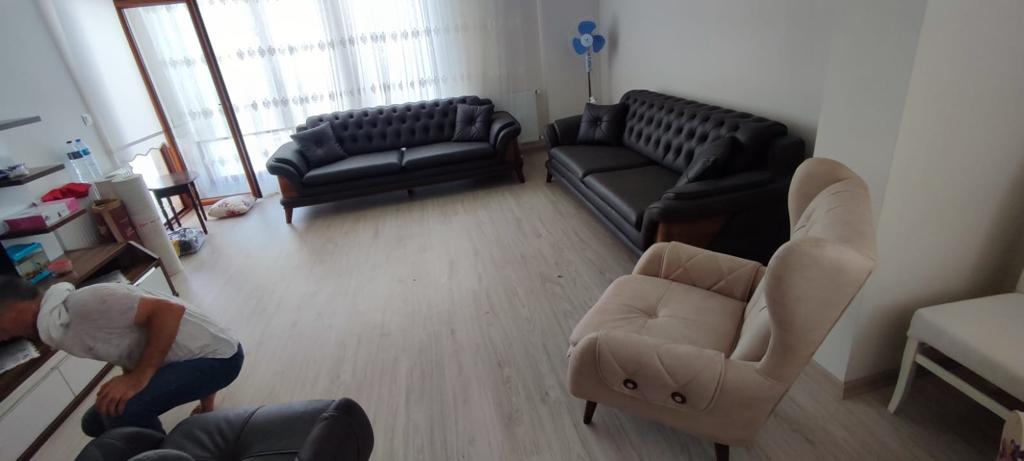 A modern living room with dark grey Chesterfield sofas and a beige single armchair. Exemplary Quality Inegol furniture.