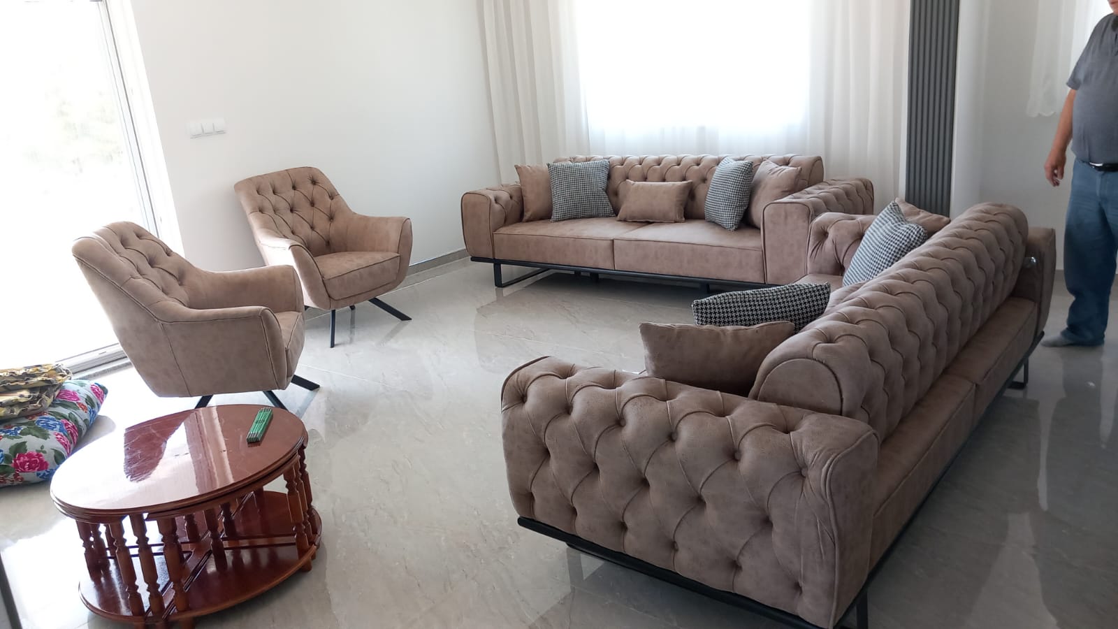 Elegant beige chesterfield style three-seater sofas and swivel armchairs in a modern living room, with a wooden coffee table. Reflecting competitive Inegol furniture prices.