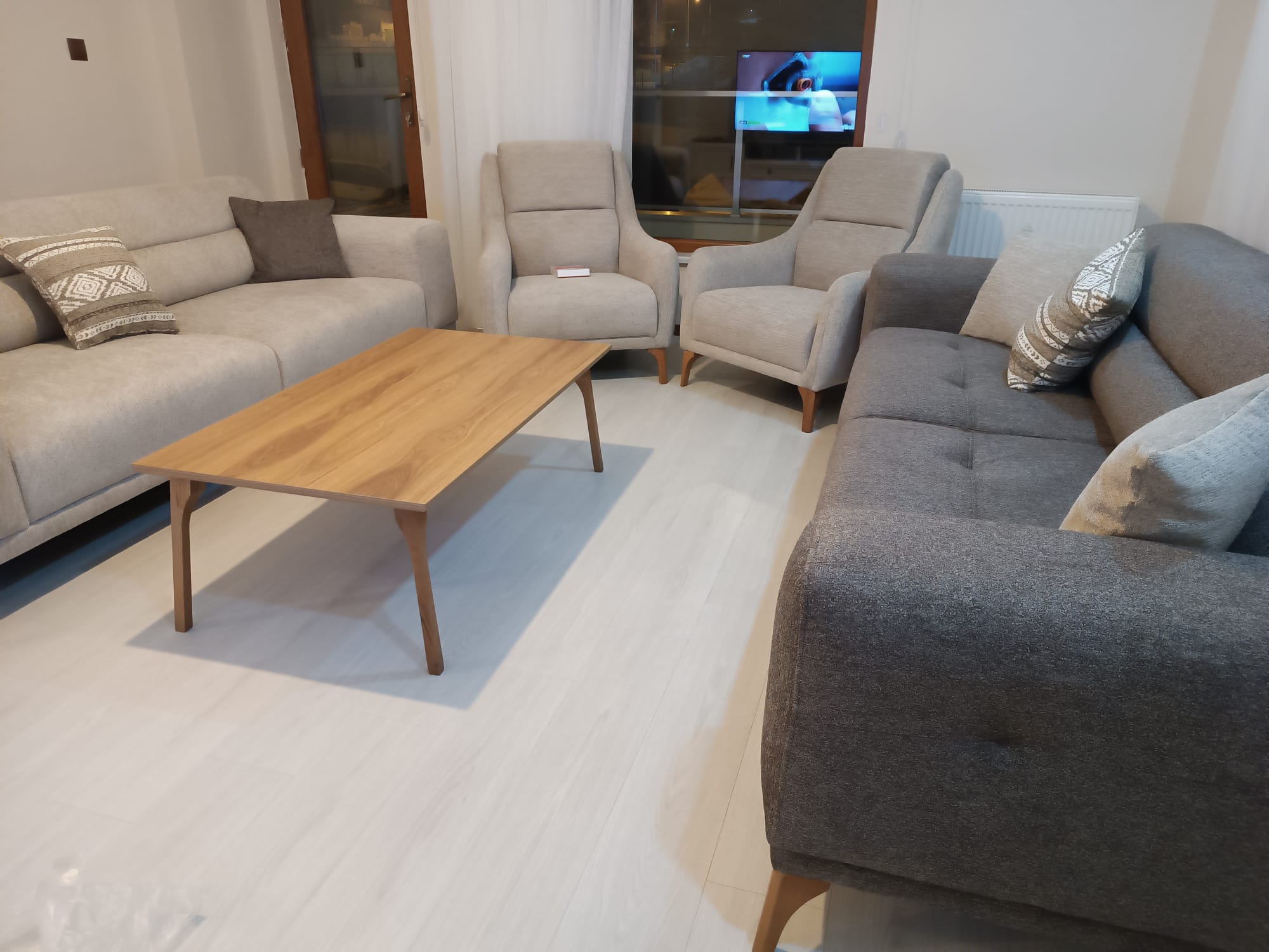 Contemporary living room featuring light and dark gray sofas, two armchairs, and a wooden coffee table, reflecting Bursa furniture quality.