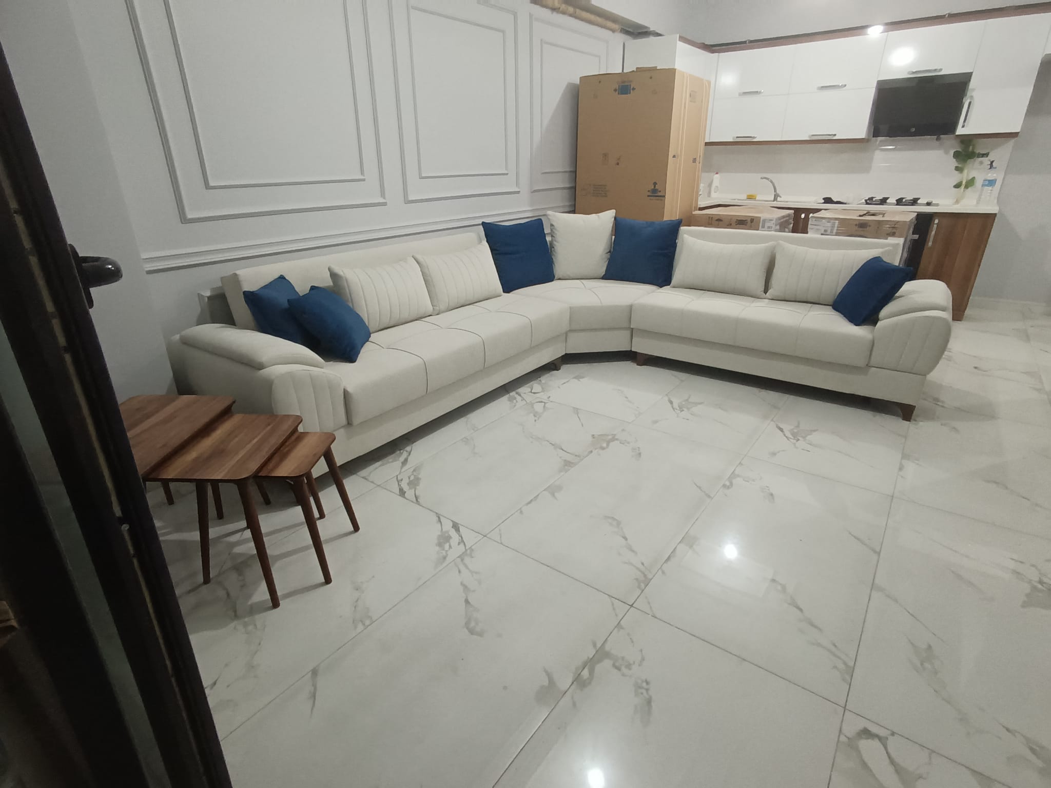 Modern cream L-shaped sectional sofa, Hacı Dinlenme Batman, featuring elegant design and blue throw pillows. Elevate your living space with Bursa furniture quality.