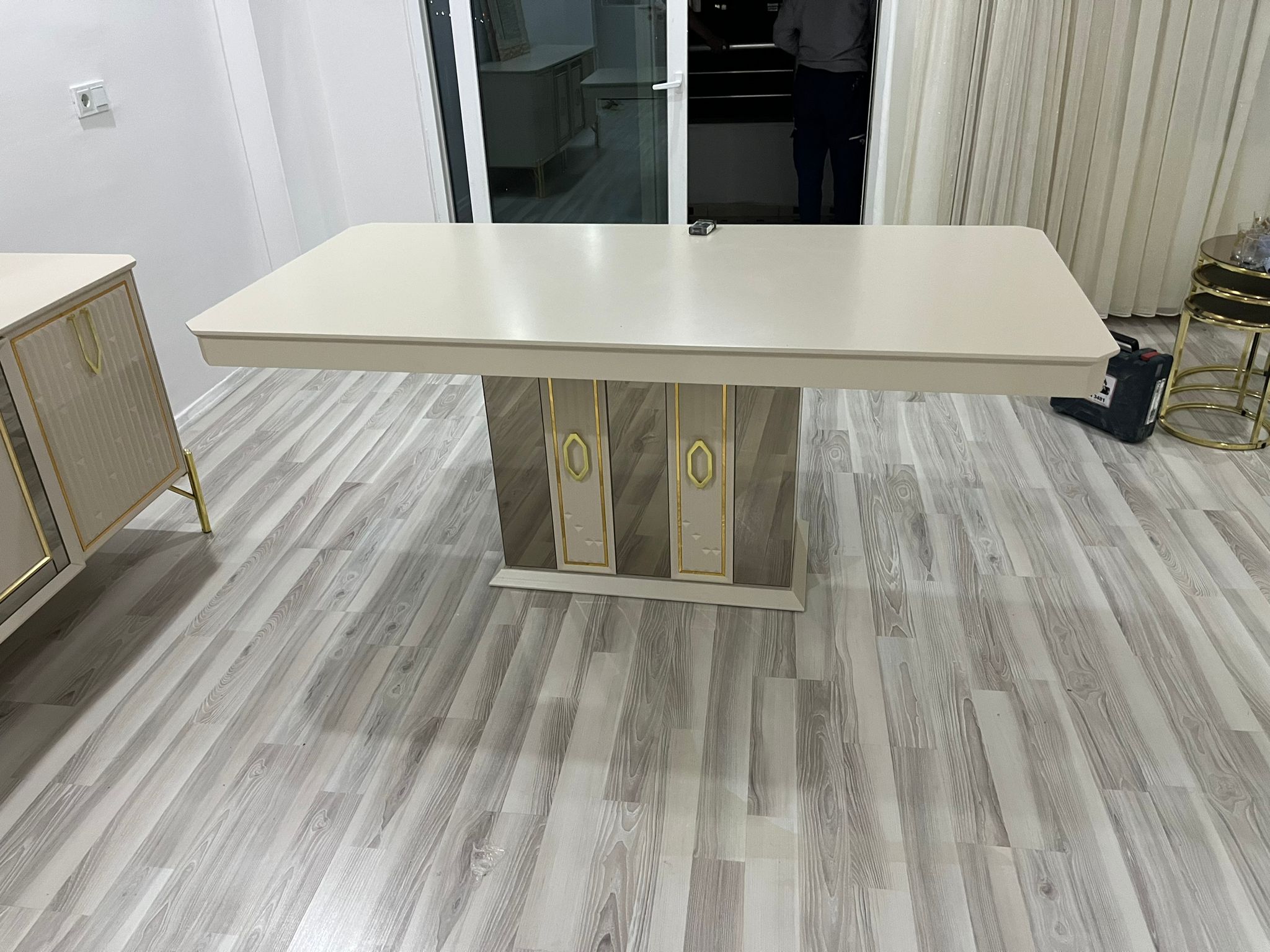 Elegant beige dining table with a modern design, featuring a mirrored base with golden accents. Perfect for inegol furniture campaigns.