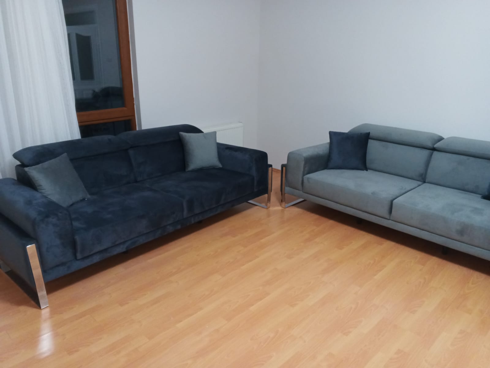 A set of modern sofas in navy blue and light grey, featuring sleek designs and polished stainless steel legs. High-quality İnegöl furniture.