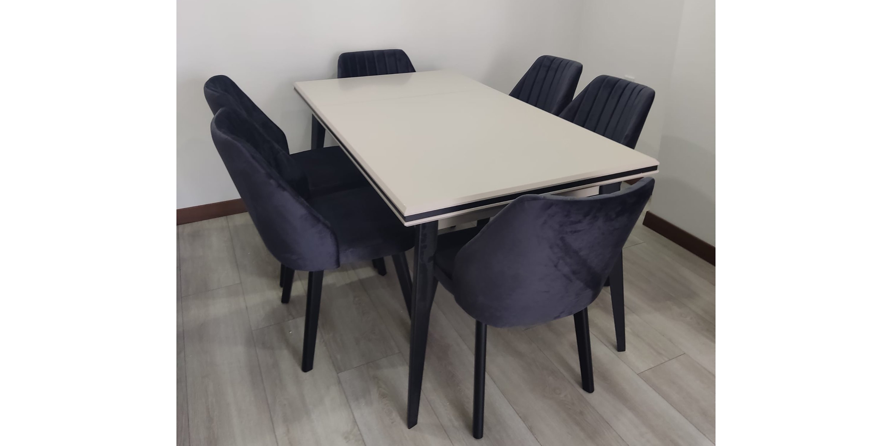 A modern dining table set featuring an extendable beige table and elegant grey velvet upholstered chairs. This stylish and functional piece stands out among Inegol furniture models.