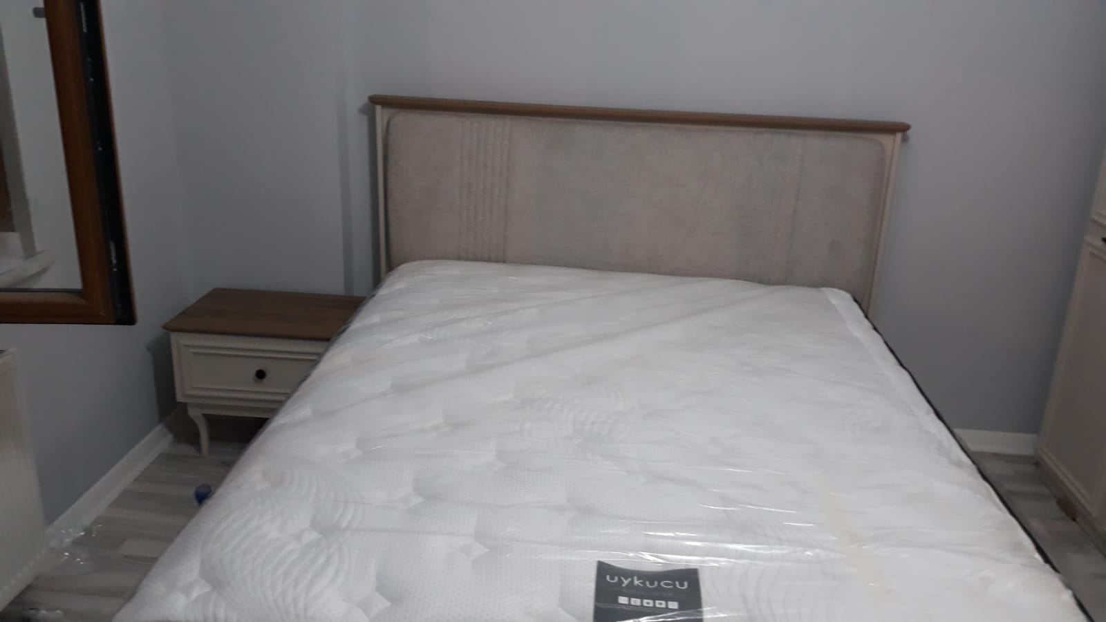 Modern design bed with upholstered headboard, wooden-detailed nightstand, and Uykuçu brand mattress. A stylish choice among Inegol furniture models.