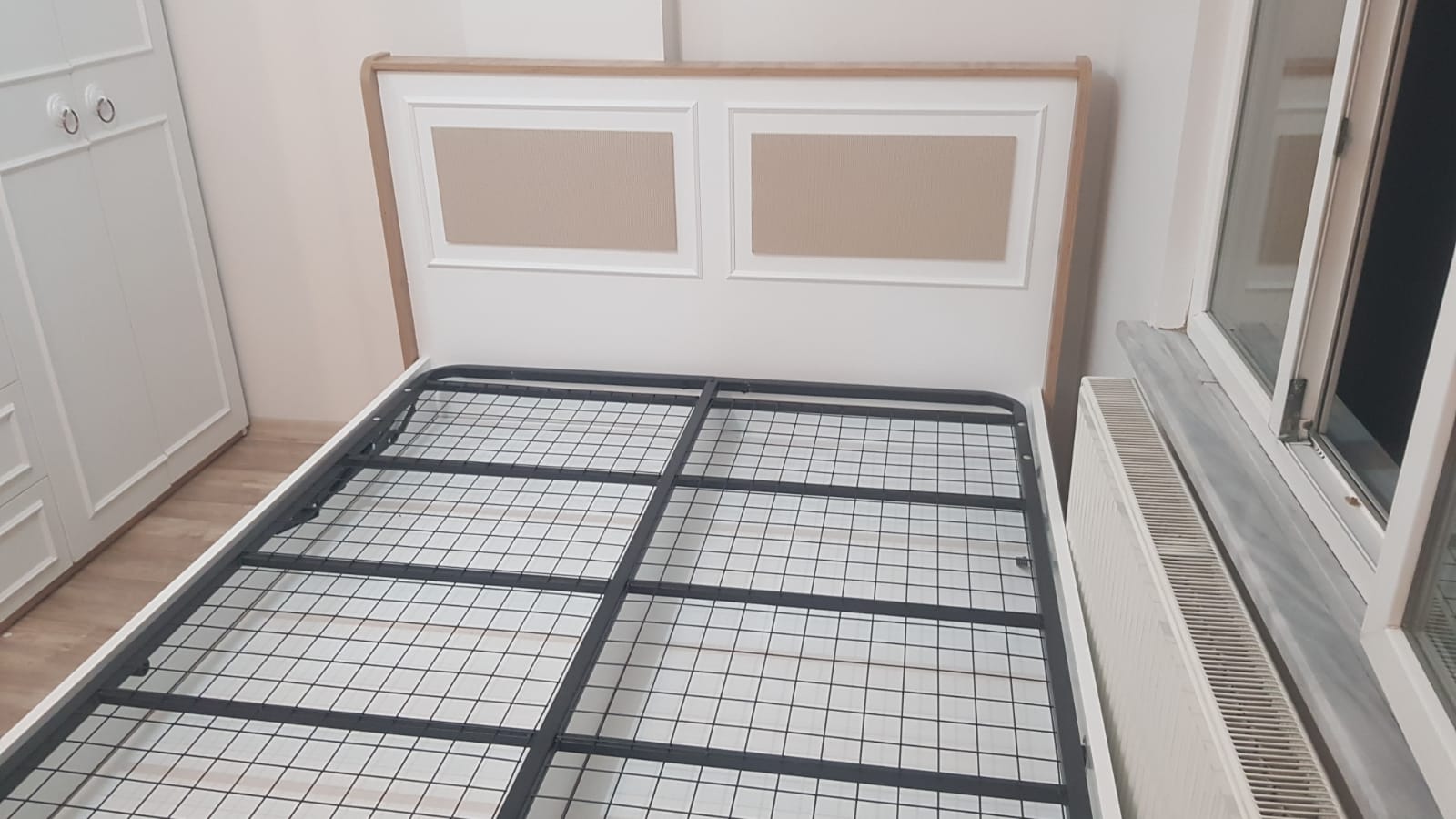 White bed frame, wooden and beige paneled headboard, sturdy metal base. Ideal for bedroom, comfortable with Inegol furniture quality.