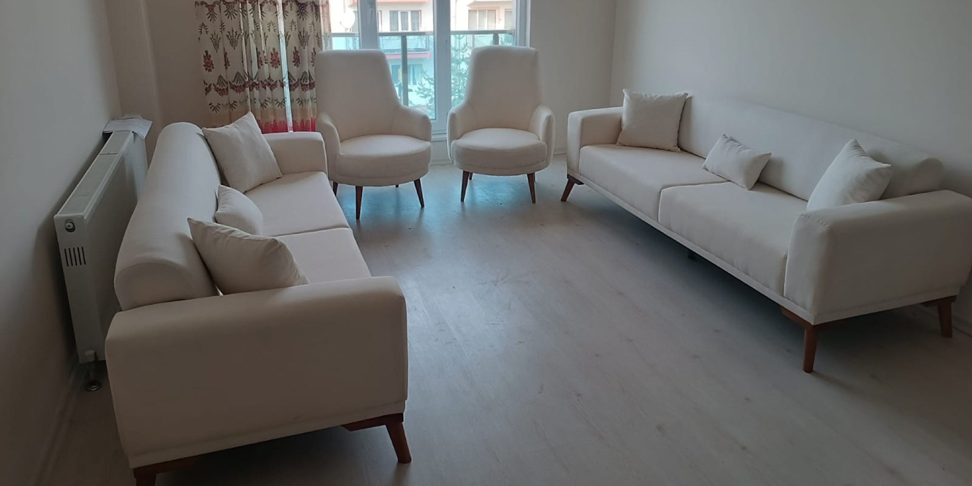 Image of a modern cream living room set, including two three-seater sofas and two armchairs, showcasing Quality Inegol furniture in a bright room.