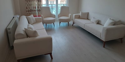 Aydınlık bir odada, krem rengi iki üçlü kanepe ve iki tekli berjerden oluşan modern Kaliteli İnegöl mobilya salon takımı görseli.