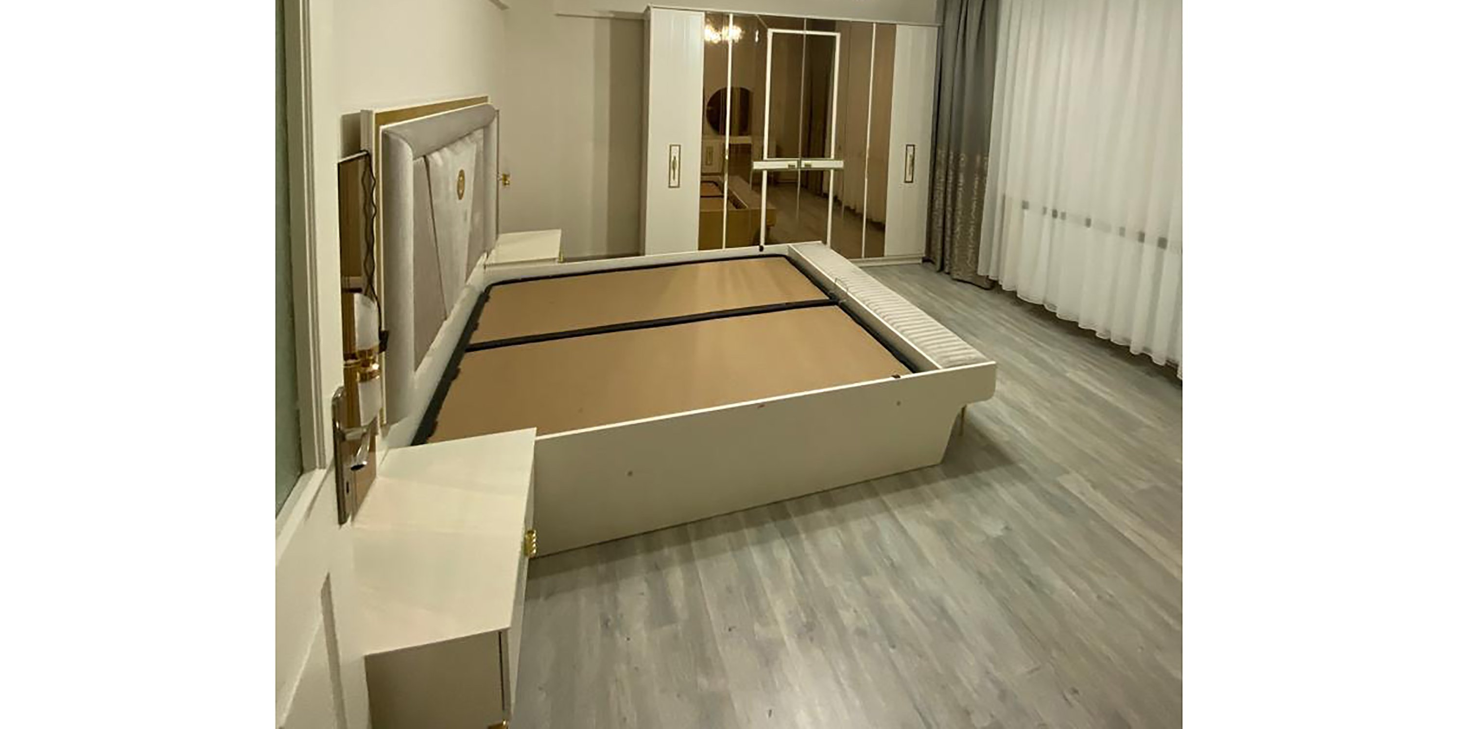 Elegant white bedroom set with a padded headboard, two nightstands, and a mirrored wardrobe. A prime example of İnegöl furniture models.