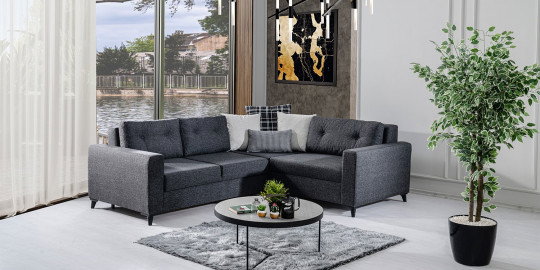 Minimalist dekorasyonlu salonda, modern koyu gri Bahar köşe koltuk takımı, yuvarlak sehpa ve bitki ile. inegol mobilya kalitesi.
