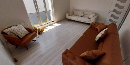 Geniş pencereli aydınlık salonda modern kahve chester kanepe, krem koltuklar ve tekli berjer. inegöl mobilya kampanyaları.